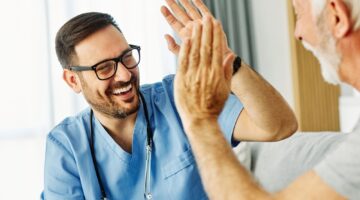 Doctor,Or,Nurse,Caregiver,With,Senior,Man,Giving,High,Five
