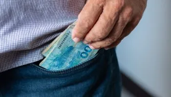 Man taking 100 Brazilian reais banknotes from his pocket