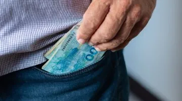 Man taking 100 Brazilian reais banknotes from his pocket