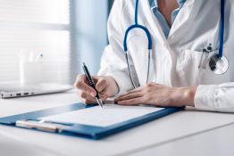 Doctor,Sitting,At,Desk,And,Writing,A,Prescription,For,Her