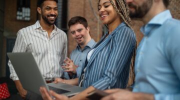 Cheerful,Young,Businesspeople,With,Laptop,Working,In,Office,,Social,Inclusion