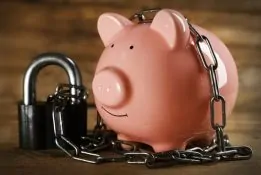 Piggy,Bank,And,Chains,On,Wooden,Background