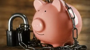 Piggy,Bank,And,Chains,On,Wooden,Background
