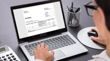Close-up,Of,A,Businesswoman,Calculating,Invoice,On,Laptop,In,Office